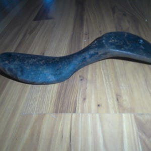 May include: A vintage metal shoe last, a tool used by shoemakers to shape and form shoes. The last is made of dark metal and has a curved shape.