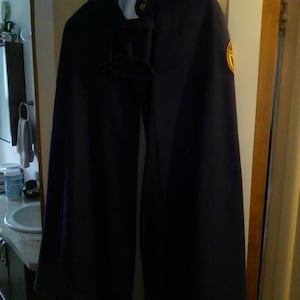 May include: A dark blue uniform with gold trim and a badge. The uniform has a high collar and a cape. The text "M.S.O.M." is embroidered on the collar.