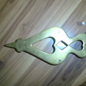May include: A brass nutcracker shaped like a heart with a diamond-shaped hole in the center.