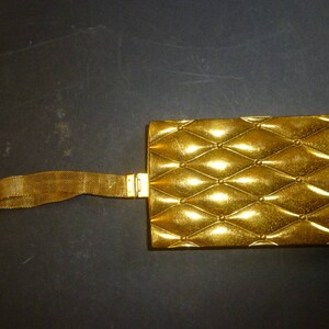 May include: A gold-colored metal clutch purse with a chain strap and a quilted design.