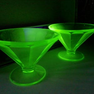 May include: Two green glass bowls with a diamond pattern. The bowls are on a dark surface.