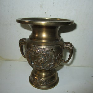 May include: A brass vase with two handles and a dragon design. The vase is about 8 inches tall.