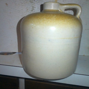 May include: A white ceramic jug with a brown glaze on the top. The jug has a handle and a wide mouth.