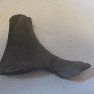 May include: A gray plastic shoe form for making shoes. The form is shaped like a foot and has a pointed toe.