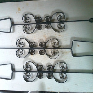 May include: Three black metal skewers with decorative swirls on the handles. The skewers are about 12 inches long.