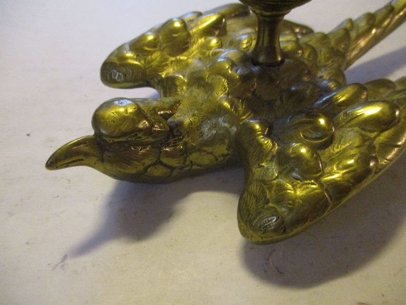 K&ouml;nnte beinhalten: Antikes, messingfarbenes, vogelartiges Dekorationsobjekt. Der Vogel hat ausgebreitete Fl&uuml;gel und eine detaillierte, strukturierte Oberfl&auml;che. Es ist wahrscheinlich ein dekoratives Element f&uuml;r M&ouml;bel oder einen &auml;hnlichen Artikel.