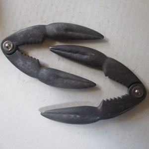 May include: A pair of black metal crab crackers. The crackers are designed to look like crab claws.