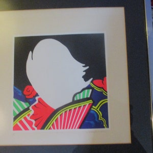 May include: A framed print of a colorful abstract art piece featuring a white silhouette of a person's head and shoulders against a black background. The artwork is surrounded by a colorful geometric pattern with red, green, blue, and yellow accents.