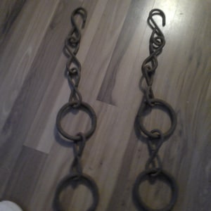 May include: Two antique metal chains with three rings each. The chains are made of twisted metal and have a rustic, aged look.