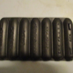 May include: A black cast iron muffin pan with six individual molds. The pan is labeled "DIE CAST  THE  'S.T.L.'  MFG.  YORK  PA.  STICK  PAN."