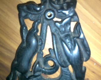 May include: Black cast iron wall mounted doorstop featuring a stylized design of two birds with a floral motif.