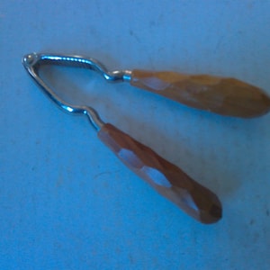 May include: A wooden nutcracker with a silver metal nutcracker mechanism. The handles are made of wood and have a textured finish.