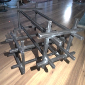 May include: A black metal sculpture with a geometric design. The sculpture is made of multiple intersecting bars, creating a three-dimensional grid.