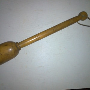 May include: A wooden potato masher with a rounded head and a long handle. The handle has a leather strap attached to the top.