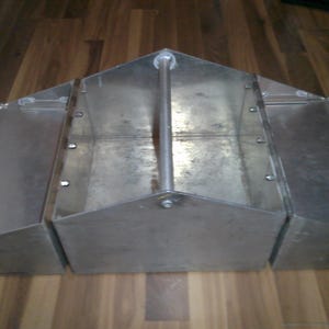 May include: A silver metal toolbox with three compartments and a carrying handle. The toolbox has a hinged lid on each compartment.