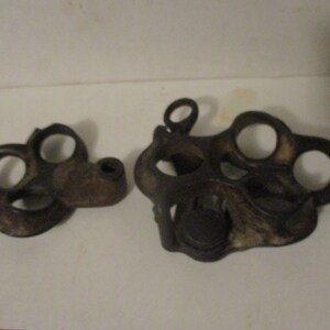May include: Two antique metal pieces with multiple circular openings. The pieces are dark brown and have a worn, rustic appearance.