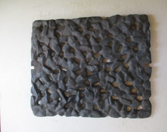 May include: A black cast iron grate with a textured surface and many small holes. The grate is designed to allow air to circulate.