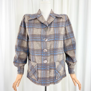 May include: A vintage-style plaid jacket in shades of gray, brown, and light blue. The jacket features a classic collar, three large buttons, and two front pockets. The sleeves are slightly puffed at the shoulders.