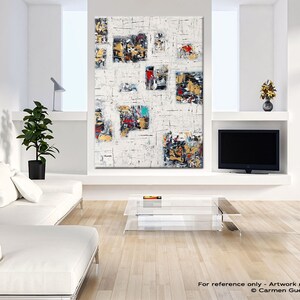 May include: Abstract painting with a white background and colorful geometric shapes. The painting is framed and hanging on a white wall in a modern living room.
