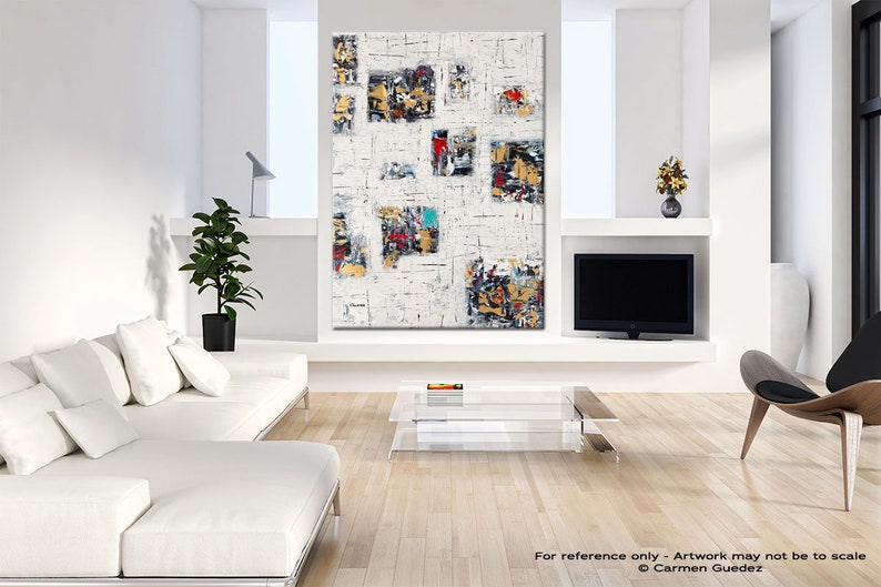 May include: Abstract painting with a white background and colorful geometric shapes. The painting is framed and hanging on a white wall in a modern living room.