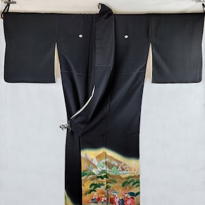 May include: A black silk kimono with a colorful scene of people and mountains. The kimono has a white lining and is decorated with gold accents.