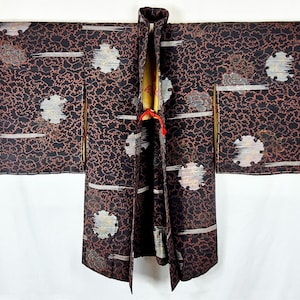 May include: A black and brown patterned kimono with a red and gold tie. The kimono features a traditional Japanese design.