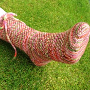 Puede incluir: Un par de calcetines de punto coloridos con un patrón rosa, verde y naranja. Los calcetines están hechos con un hilo suave y tienen un ajuste cómodo.