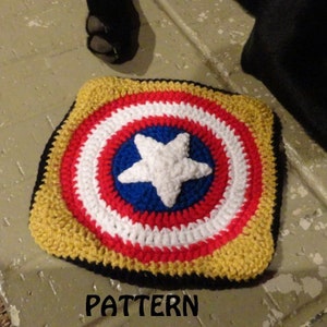 May include: A crocheted square with a red, white, and blue star design, resembling Captain America's shield. The square is surrounded by a yellow border and a black outer edge. The word "PATTERN" is written below the square.