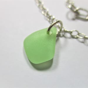May include: A silver chain necklace with a light green sea glass pendant.