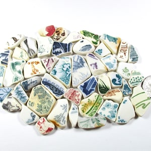 May include: A collection of assorted ceramic shards featuring various patterns in blue, green, red, brown, and black on white backgrounds. A silver-colored United States dime is placed next to the pieces for scale, measuring 0.705 inches in diameter.