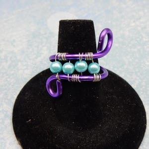 Anillo de alambre con perlas de vidrio, azul, morado y pergamino