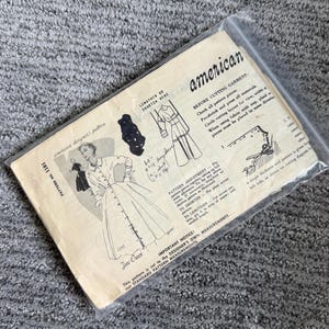 May include: A vintage American Designer's Pattern 1181 for a button-front dress by Toni Owen, enclosed in a clear plastic sleeve. The paper envelope features black line illustrations of the garment, handwritten notes, and printed sewing instructions.