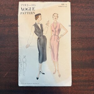 Könnte beinhalten: Vintage Vogue Schnittmuster 7193. Das Schnittmuster zeigt Illustrationen von zwei Kleidern, eines in Schwarz und das andere in Rosa. Die Hülle des Schnittmusters enthält den Text "Vogue Pattern" und Größenangaben. Der Hintergrund ist eine dunkle Holzoberfläche.