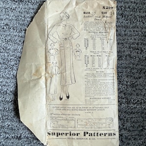 Könnte beinhalten: Ein Vintage-Schnittmusterumschlag von Superior Patterns für ein Kleid, beschriftet mit K232, Größe 14, Oberweite 32. Der beigefarbene Papierumschlag zeigt schwarze Illustrationen eines Kleiderdesigns, technische Nähanleitungen, Materialbedarf und das Branding von Sears, Roebuck & Co.