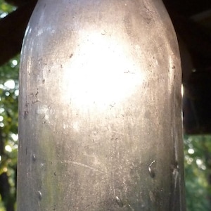 Könnte beinhalten: Eine antike Coca-Cola-Flasche aus klarem Glas mit dem geprägten Coca-Cola-Logo auf der Vorderseite. Die Flasche hat eine klassische Form und weist Alterserscheinungen auf, mit einem leicht verwitterten Aussehen. Ein Vintage-Sammlerstück.