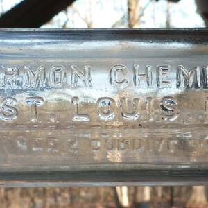 May include: A clear glass bottle with the text "KATHARMON CHEMICAL CO. ST. LOUIS, MO." embossed on the front.