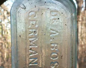 May include: A clear glass bottle with a textured surface. The bottle is labeled "Dr. Boschee's German Syrup".