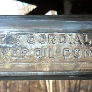 May include: A clear glass bottle with a label that reads "Hagee's Cordial 32% Extra Strong Cod Liver Oil Compound".