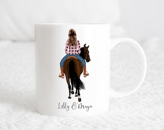 May include: White ceramic mug with a colorful illustration of a person riding a brown horse. The text "Lilly & Magic" is printed on the bottom of the mug.