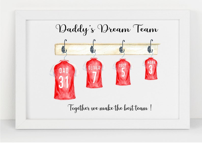 May include: A white framed print with the text "Daddy's Dream Team" and four red soccer jerseys hanging on a wooden rack. The jerseys have the names "Dad", "Oliver", "Lucy", and "Noah" and numbers 31, 7, 5, and 3 on them. The text "Together we make the best team!" is at the bottom of the print.