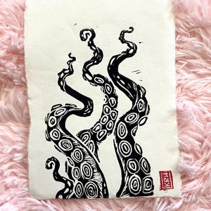 May include: Black and white linocut print of two octopus tentacles reaching up. The print is on cream coloured paper with a red stamp in the bottom right corner that says "KRW".