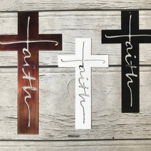 Puede incluir: Tres cruces decorativas en marr&oacute;n, blanco y negro. Cada cruz presenta la palabra "faith" recortada en una fuente cursiva. Las cruces se muestran sobre un fondo claro de vetas de madera.