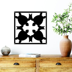May include: Black metal wall art featuring a geometric design of four stylized turtles. The art is mounted on a white wall above a wooden dresser with a book and a decorative vase.
