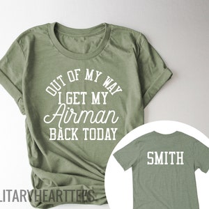 May include: Two green t-shirts. The front shirt has the text "Out of my way I get my Airman back today". The back shirt has the text "Smith".