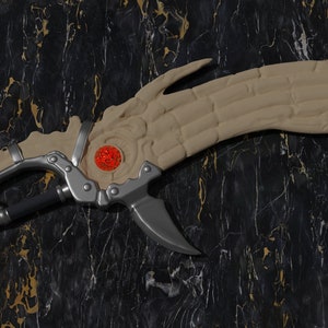 May include: A decorative sword with a bone-like blade and a red gem embedded in the handle. The sword has a silver metal handle and a black metal shaft.