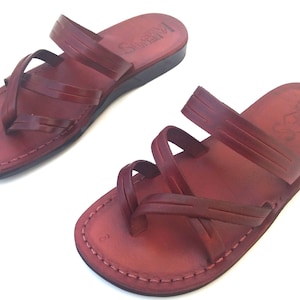 May include: A pair of brown leather sandals with multiple straps. The sandals have a simple design and are made of high-quality leather.