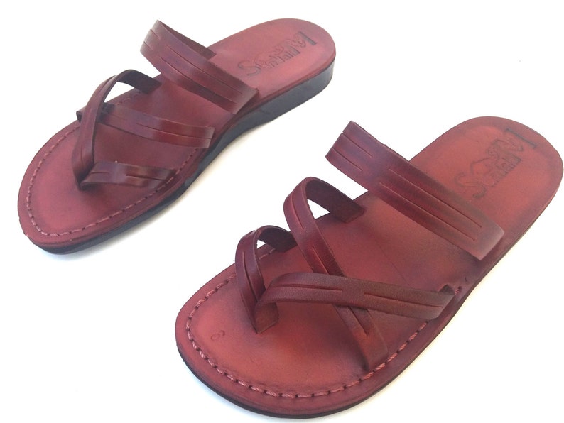 May include: A pair of brown leather sandals with multiple straps. The sandals have a simple design and are made of high-quality leather.