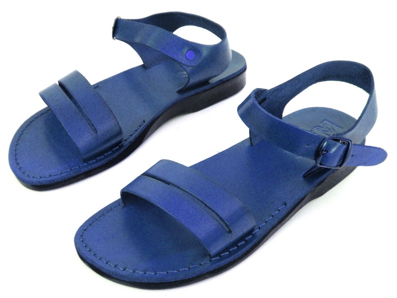 May include: A pair of blue leather sandals with adjustable ankle straps. The sandals have a simple design with a single strap across the top of the foot.