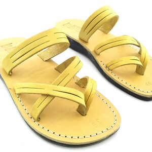 May include: A pair of tan leather sandals with multiple straps. The sandals have a simple design and are made of high-quality leather.