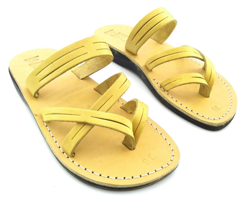 May include: A pair of tan leather sandals with multiple straps. The sandals have a simple design and are made of high-quality leather.